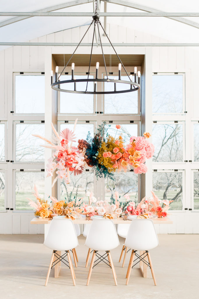 Colorful hanging floral arrangements and tabletop centerpieces at Camino Real Ranch, one of the top austin wedding venues. 