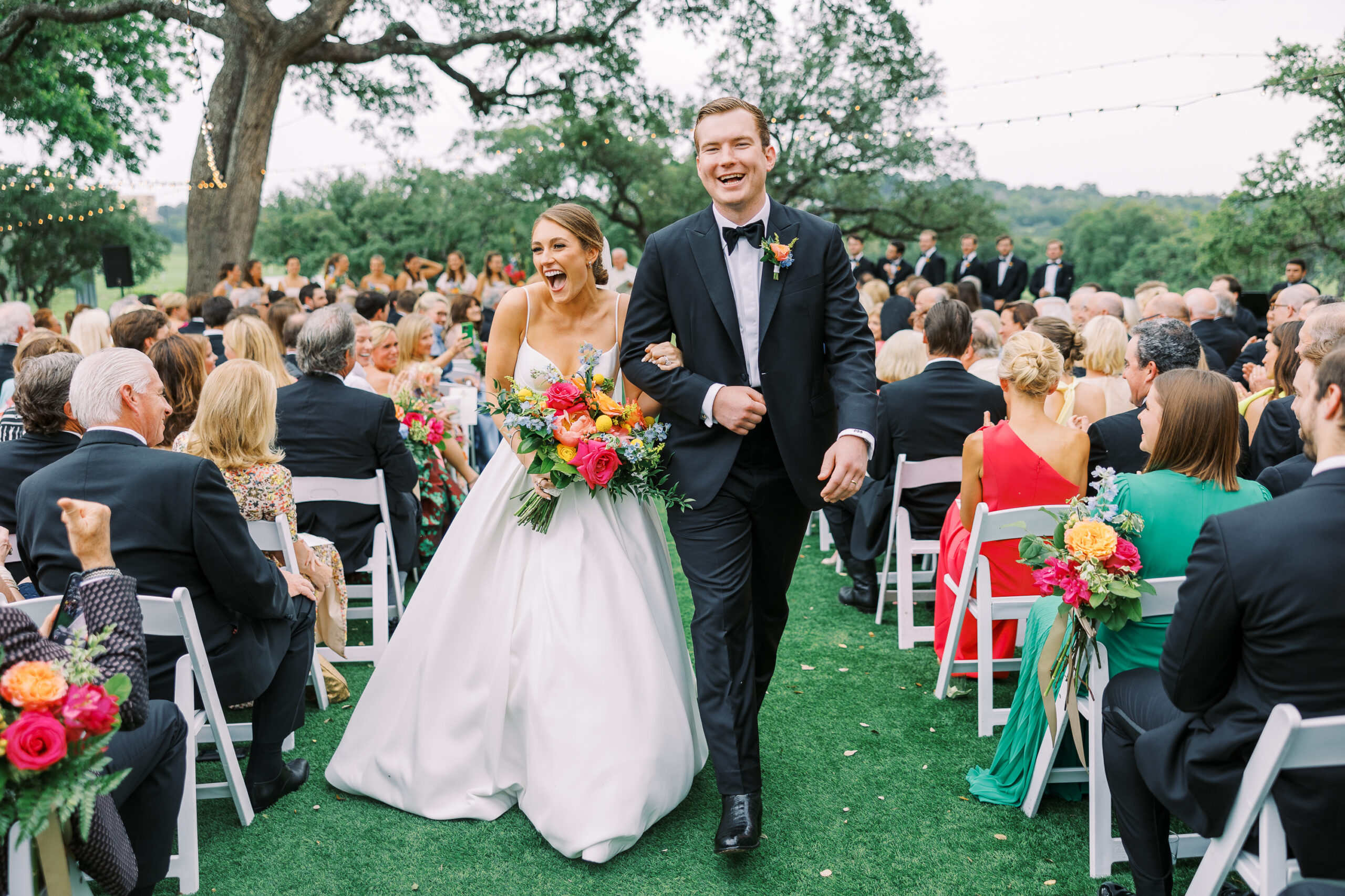 bride and groom walking down a wedding aisle with colorful flowers.